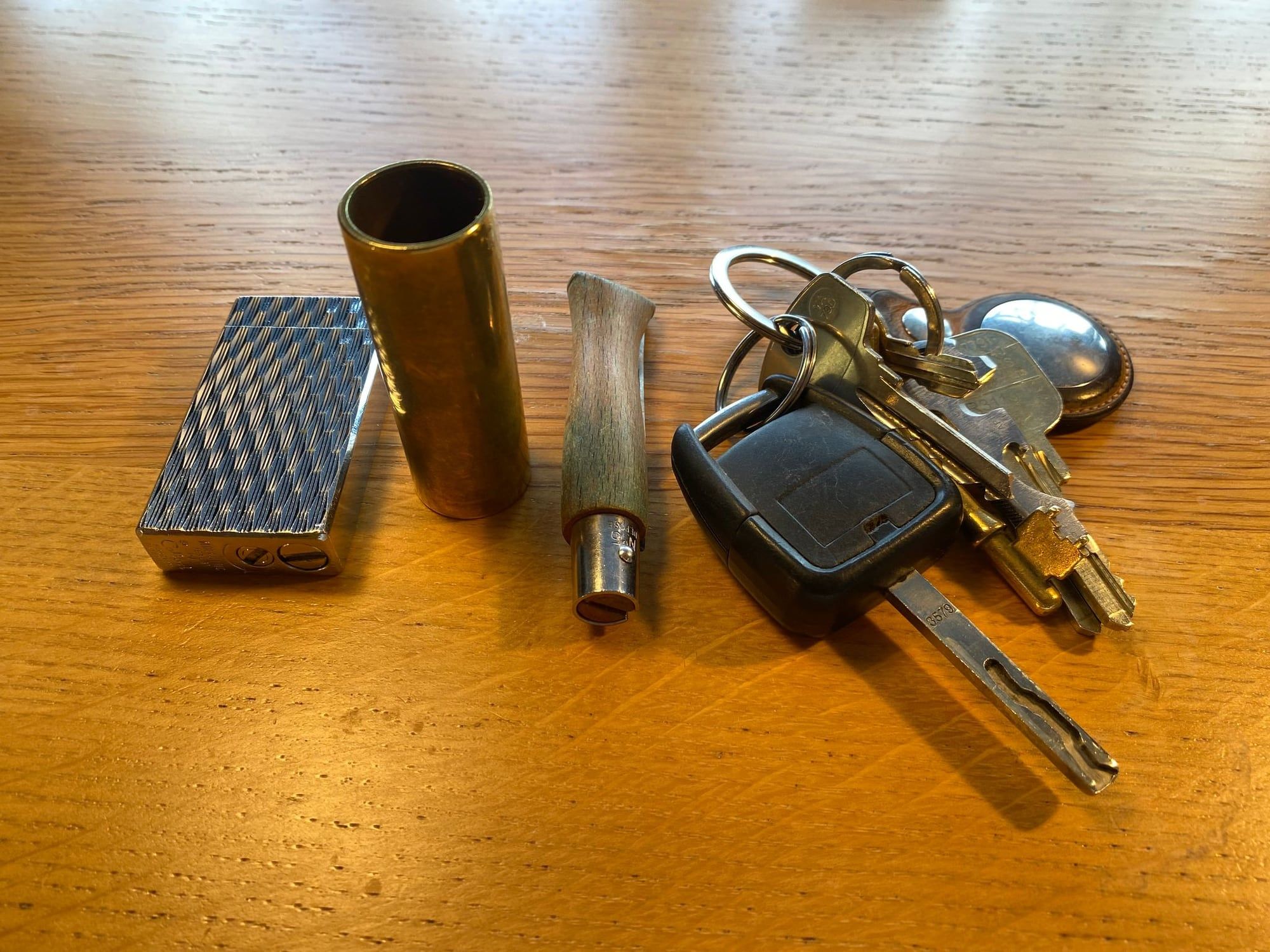 Keys with an AirTag, a guitar slide, an Opinel knife and a vintage lighter