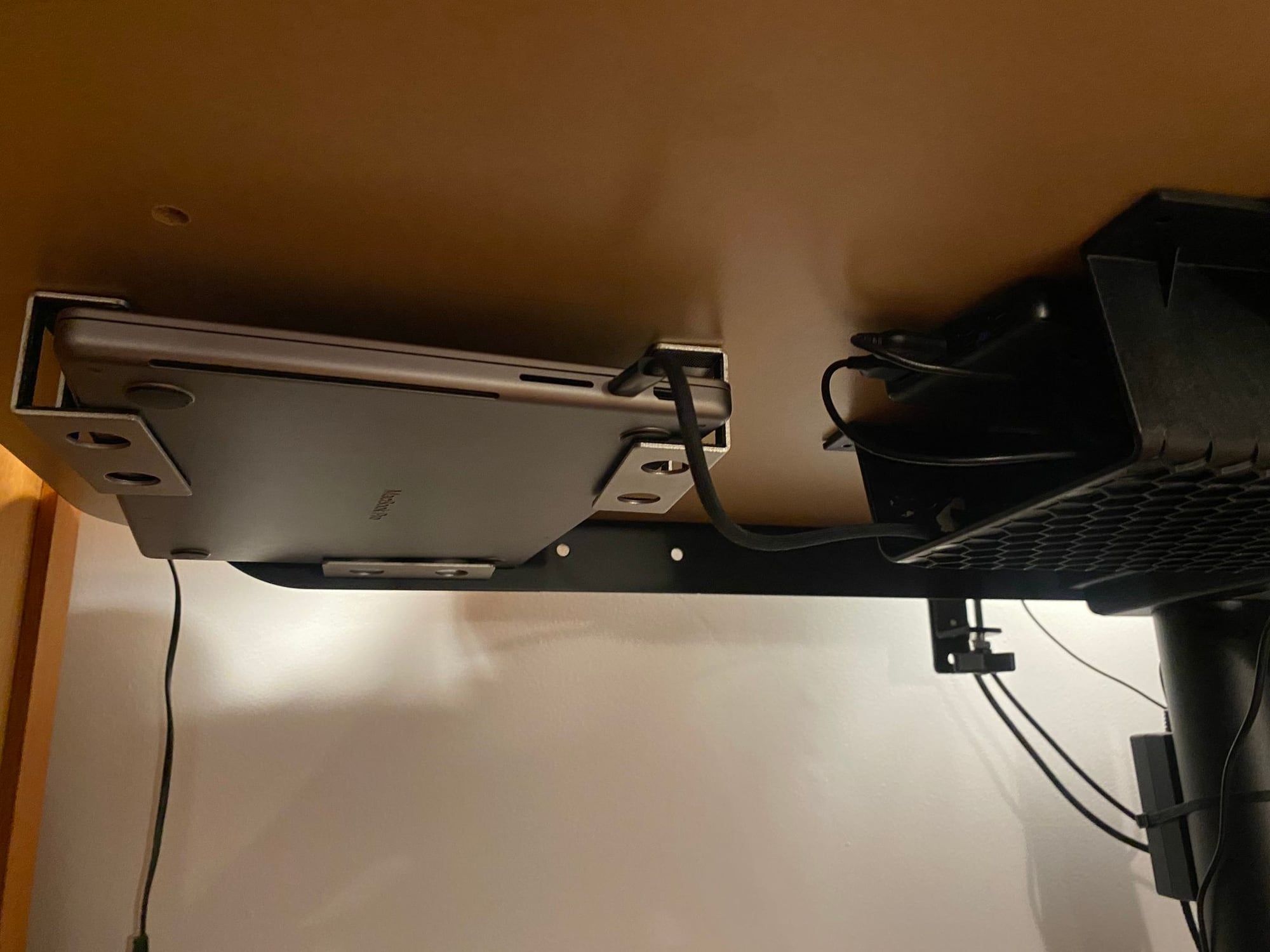 The laptop held in an under-desk cradle