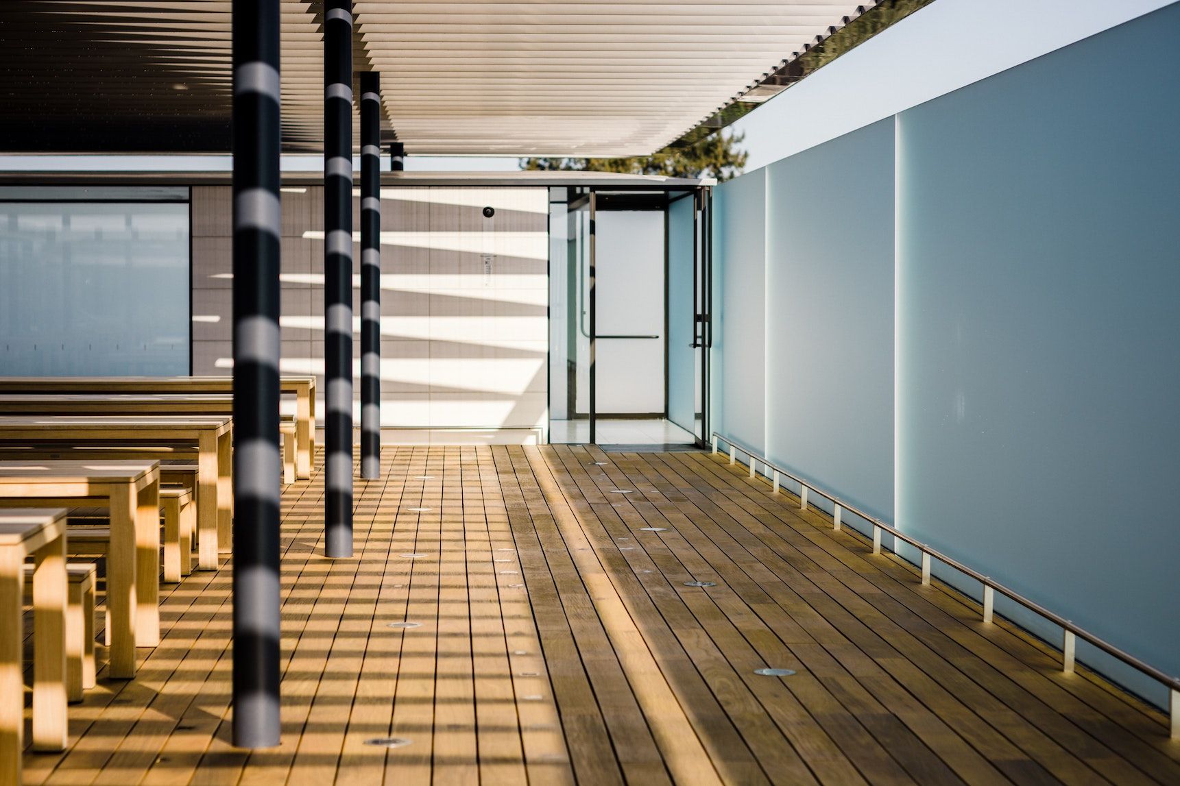Architectural photograph showing wooden deck, striped columns, and glass panels