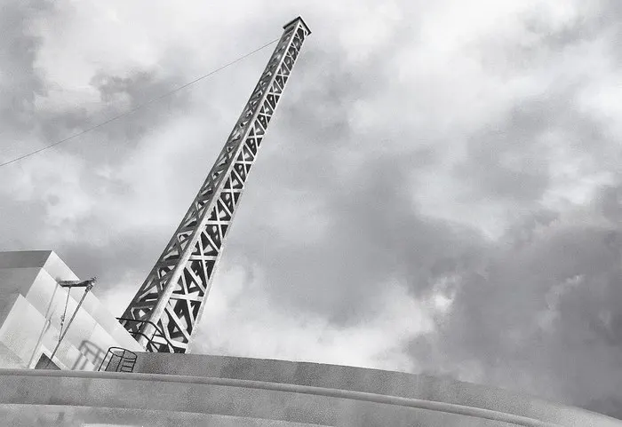 Black and white photo of a transmitter pylon above a 1950s building.